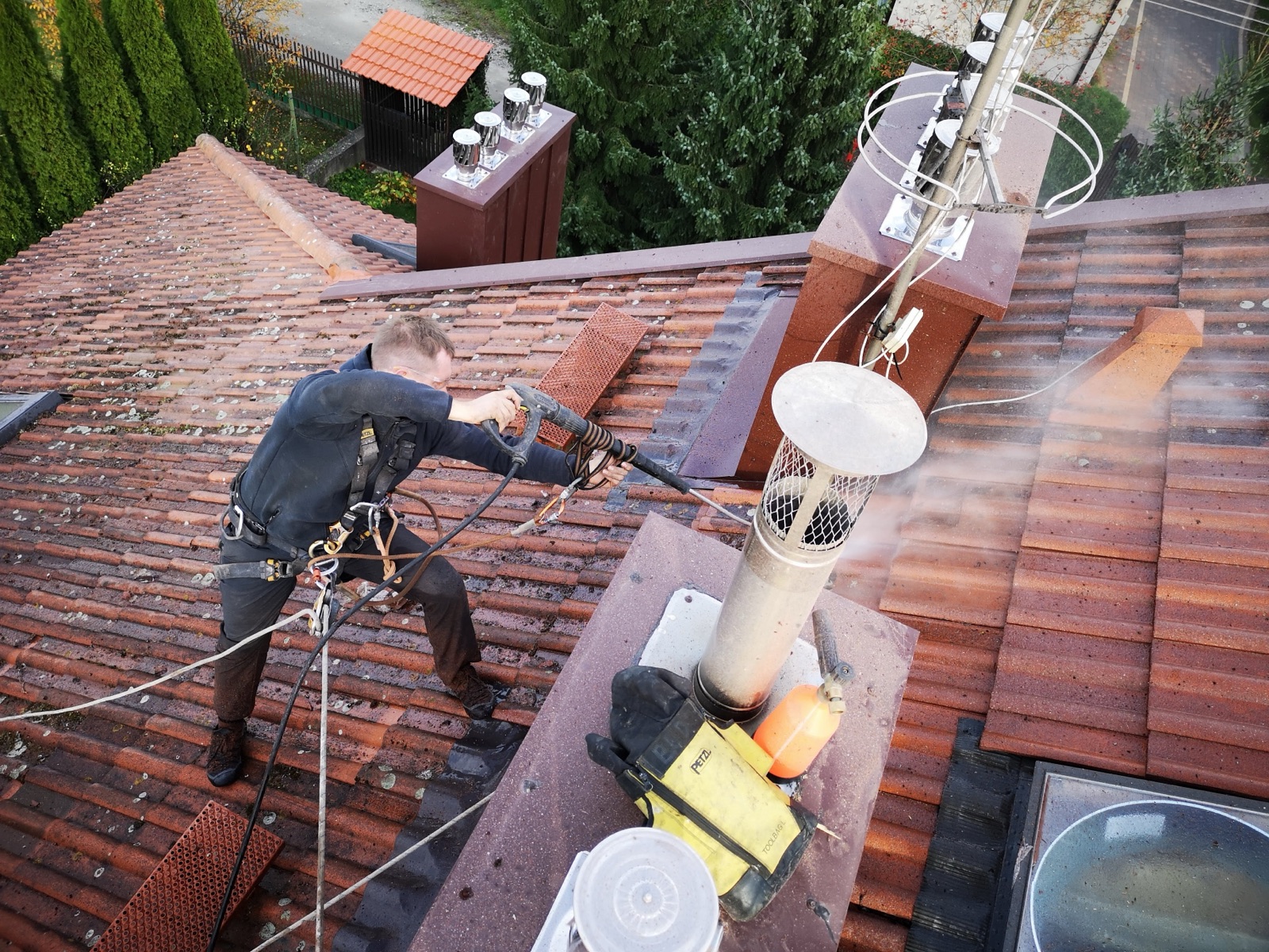 Alpinista Alpiwork w uprzęży myje ciśnieniowo dachówkę ceramiczną z mchu i porostów – czyszczenie dachów Łódź